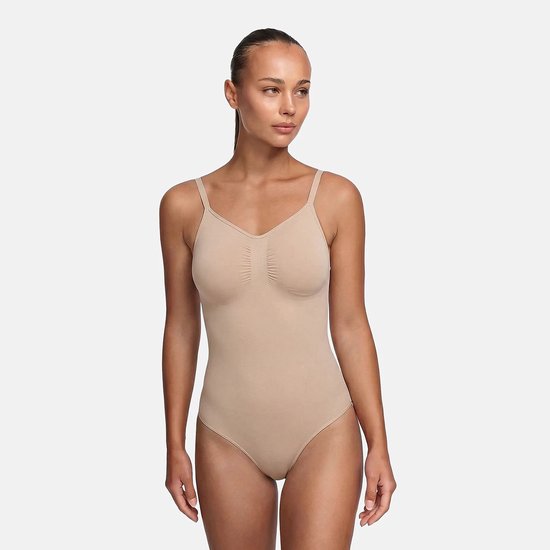 Model in een beige corrigerende bodysuit met v-hals, dunne bandjes en gerimpelde details bij de buste.