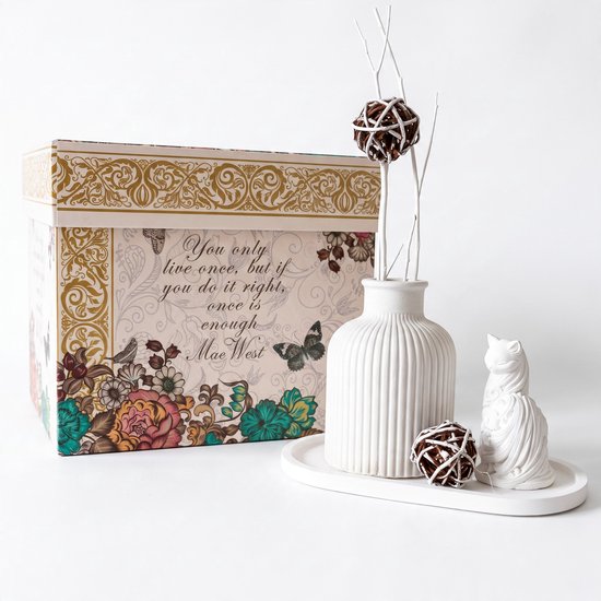 Barok geschenkdoos met Mae West citaat, witte geribbelde vaas, kattenbeeldje en decoratieve bollen op een dienblad.