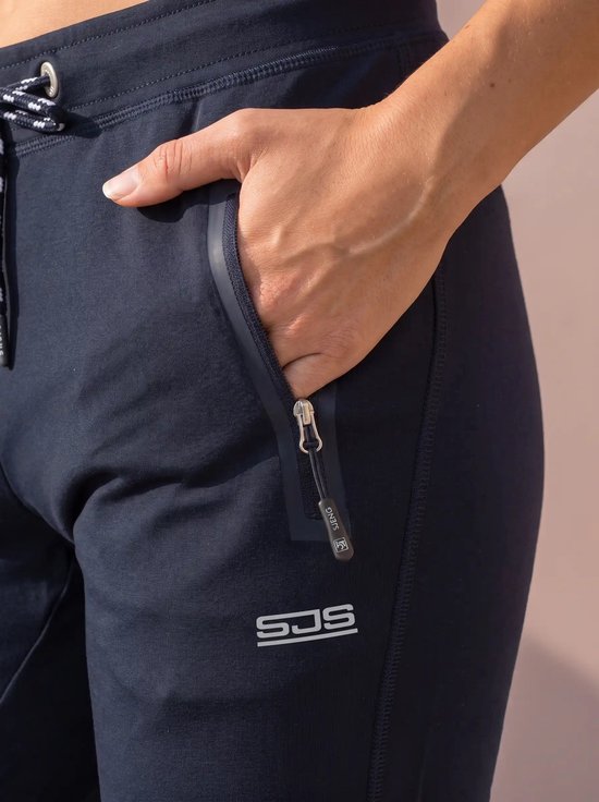 Gedetailleerde opname van de ritszak met Sjeng branding op een marineblauwe sportbroek.
