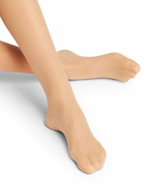 Voeten in transparante beige panty, gekruist op een witte achtergrond.