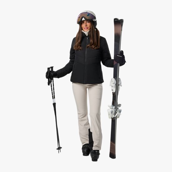 Dames in zwarte ski-jas en beige broek, met ski's en stokken in de hand.