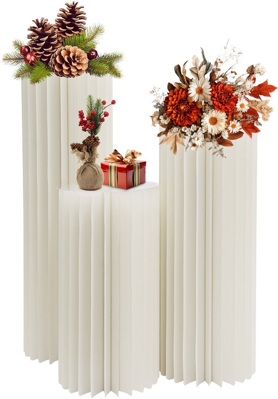 Drie crèmekleurige zuilen versierd met bloemstukken en een rood kerstcadeautje.