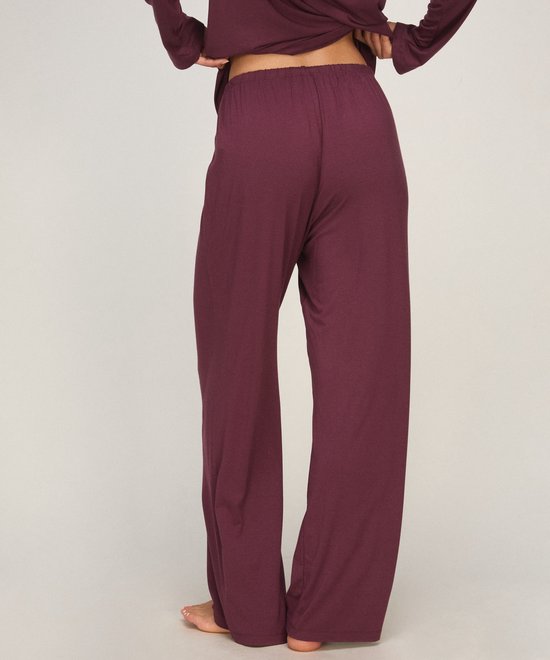 Model van achteren gezien in een bordeauxrode pyjamabroek met een elastische tailleband.