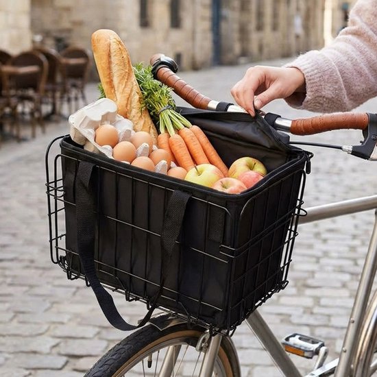 Zwarte fietsmand met voedsellading: brood, eieren, wortels en appels.