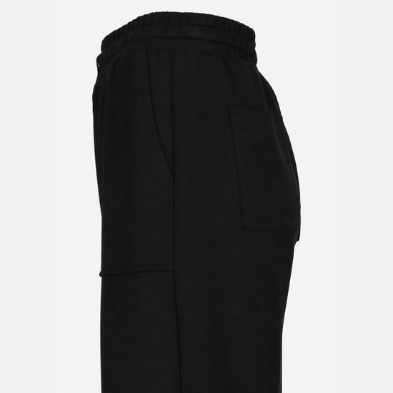 Detail van een zwarte joggingbroek met wijde pijpen en steekzakken.