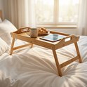 Bamboe bedtafel op wit laken met croissant, koffie en tablet.