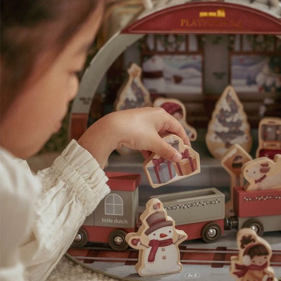 Kind legt houten kerstfiguur met cadeautjes in een Little Dutch trein. Adventskalender.