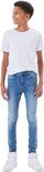 Jongen met gekruld haar, draagt een witte t-shirt en een skinny spijkerbroek met blauwe wassing.