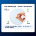 Vinger die een lichtgekleurd Vitamine B12 1000 mcg kauwtablet vasthoudt. Met icoontjes voor vegan, zoutvrij en suikervrij.