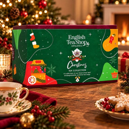 Groene English Tea Shop geschenkdoos met kerstillustraties op een tafel met thee en kerstkoekjes.