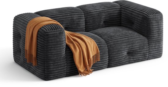 Donkergrijze corduroy bank met ribbelstructuur, met een oranje plaid over de armleuning.