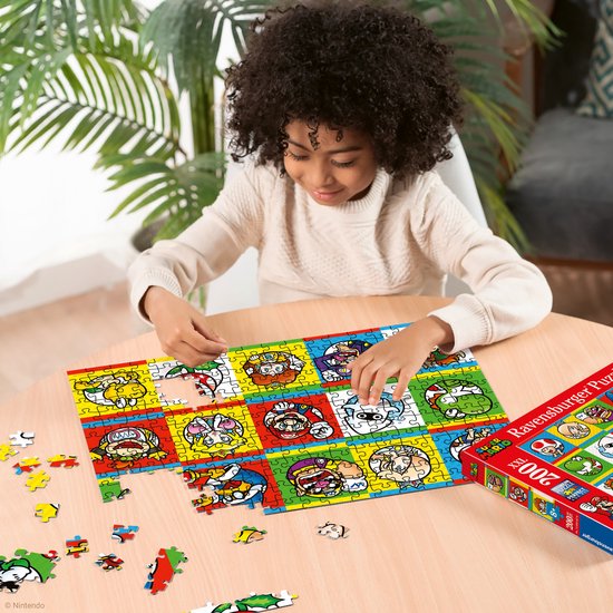 Meisje legt een Ravensburger 200 XXL Super Mario puzzel met karakters op een kleurrijke achtergrond, zittend aan een tafel. Naast haar staat de puzzeldoos.