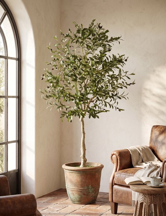Levensgrote kunst olijfboom met groene bladeren en donkere olijven in een terracotta pot, in een woonkamer.