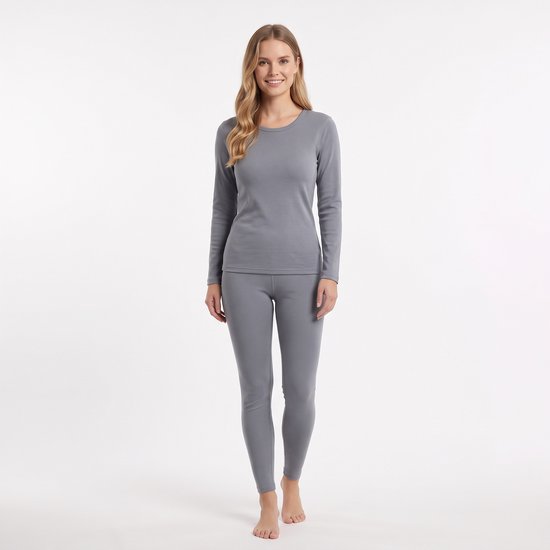 Een model draagt een grijze thermop set van lange mouwen top en legging, staand, van voren gezien.