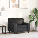 Zwarte fauteuil in een woonkamer met abstracte muurkunst en een grote plant.