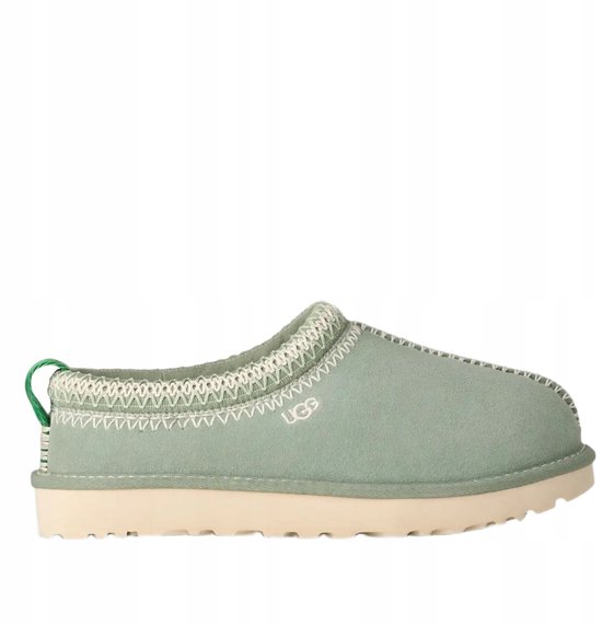 Lichtgroene UGG pantoffel met crèmekleurige zool, witte stiksels en groene lus aan de achterkant.