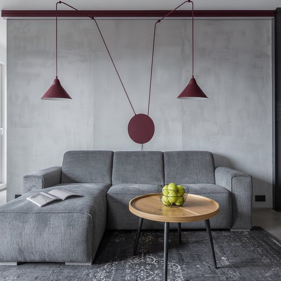 Bourgondische hanglamp met twee kappen boven een grijze bank in een woonkamer.