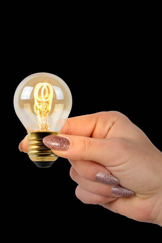 Hand met glitter nagels houdt een amberkleurige G45 LED lamp met zichtbaar filament vast.