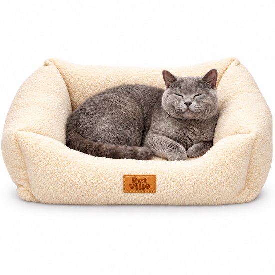 Grijze kat slaapt in een crèmekleurige, pluizige rechthoekige Petville-mand met een lederen merklabel op een witte achtergrond.