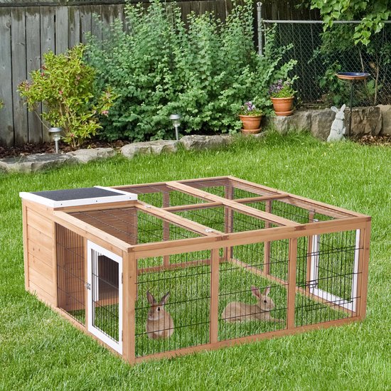 Houten ren met dak in een groene tuin met twee konijnen.