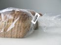 Bruin gesneden brood in een doorzichtige plastic zak, afgesloten met een witte Innoseal-sluiting.