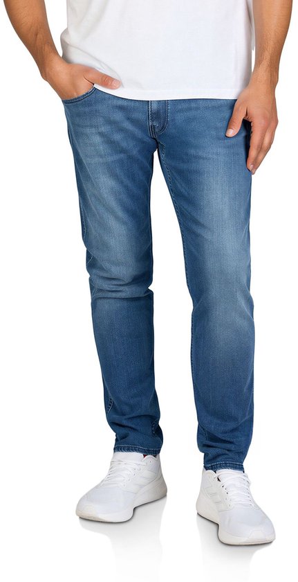 Model draagt een blauwe Replay Anbass slim fit jeans met wit T-shirt en witte sneakers.