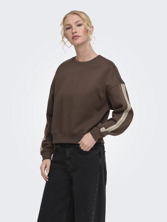 Model draagt een donkerbruine sweater met ronde hals en beige kanten details langs de mouwen.
