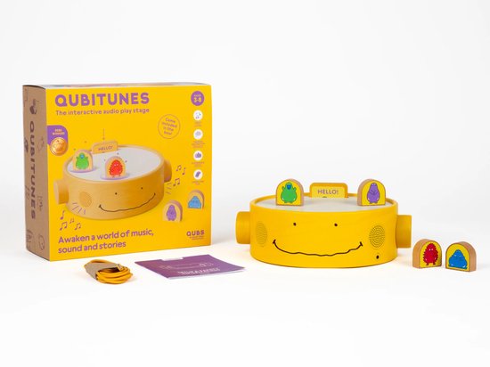 Gele Qubitunes audio speelstage met luidsprekers, oplaadkabel en schattige monsterfiguurtjes.