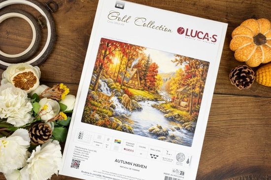 Het Luca-S 'Autumn Haven' kruissteekpakket met een voorbeeldafbeelding, op een houten achtergrond.