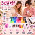 Twee vrouwen maken DIY-projecten met strasssteentjes in 60 kleuren, inclusief telefoonhoesjes en een notitieboek.