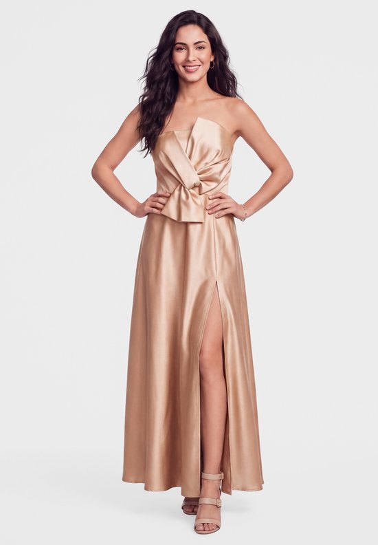 Model draagt een goudkleurige, strapless satijnen jurk met strikdetail bij de buste en een hoge split in de rok.