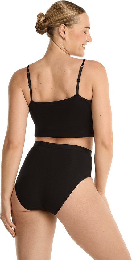 Model in zwart hemdje en slip met hoge taille, achterkant zichtbaar.