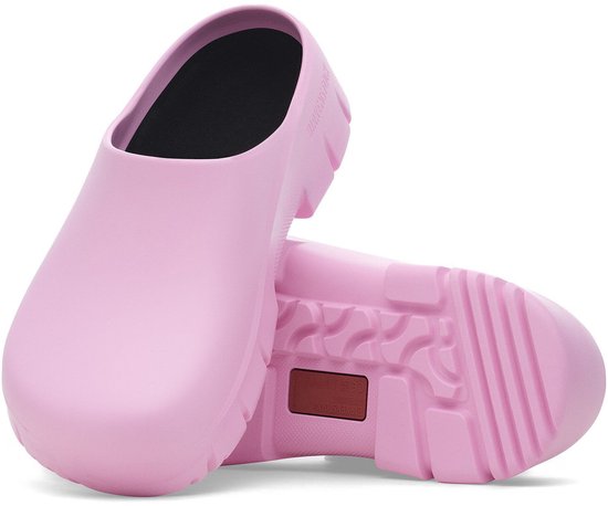 Deux sabots Birkenstock roses, l'un à l'envers, semelle et nom de marque visibles.