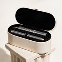 Grijze airstyler en opzetstukken in een beige opbergkoffer.