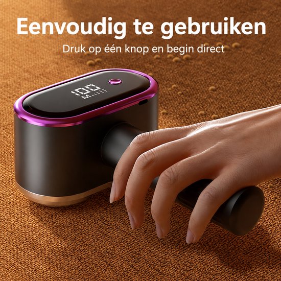 Zwarte pluizenverwijderaar met paarse rand en digitaal display, vastgehouden door een hand. Makkelijk te gebruiken.