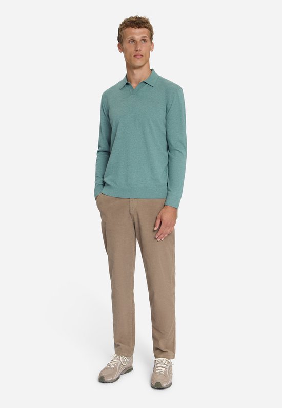 Model met lange mouwen en V-hals trui in petrolgroen, gedragen met corduroy broek.
