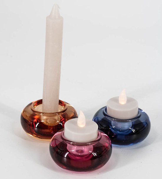 Drie gekleurde glazen kandelaars in amber, roze en blauw met kaarsen.