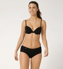 Lachend model draagt een zwarte bh en een bijpassende zwarte Sloggi midi-slip.