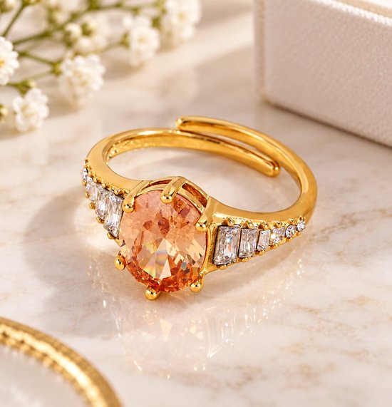Verstelbare goudkleurige ring met een grote ovaalvormige roze zirkonia geflankeerd door rijen baguette-zirkonia's.