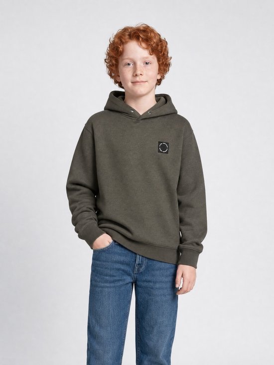 Jongen met rossig haar draagt een olijfgroene hoodie met capuchon en een zwart rond logolabel op de borst.