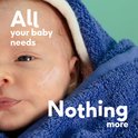 Baby met crème op het gezicht, gewikkeld in een blauwe handdoek met tekst: "All your baby needs, Nothing more".