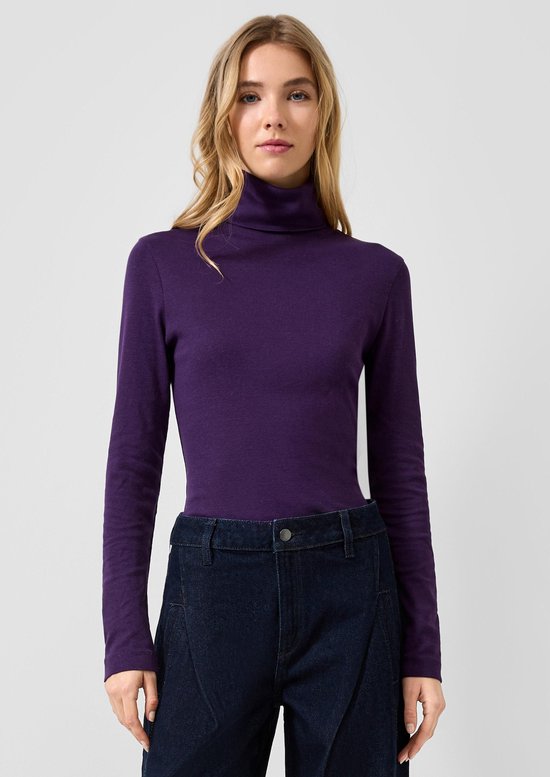 Model draagt een paarse coltrui gecombineerd met een donkerblauwe jeans.