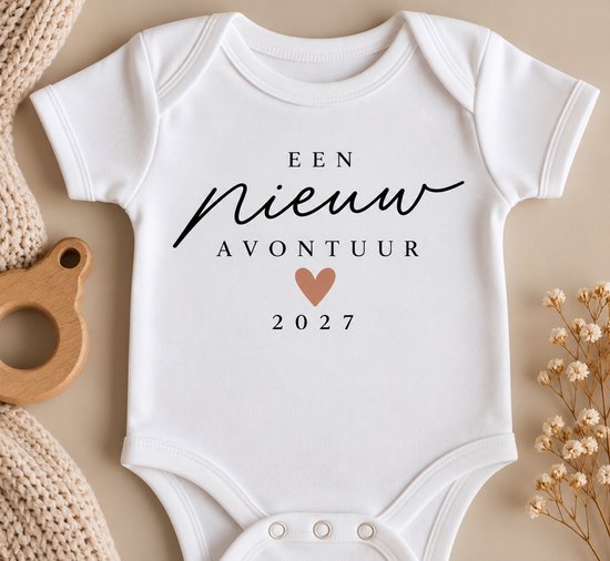 Wit babyrompertje met zwarte tekst 'EEN nieuw AVONTUUR' en een hartje boven '2027'.