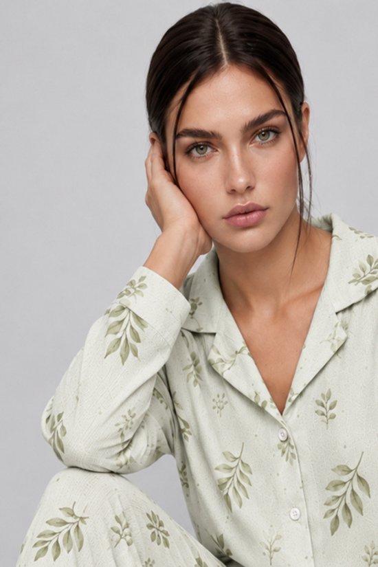 Close-up van het model in een saliegroene pyjama met bladerenprint en knoopsluiting.