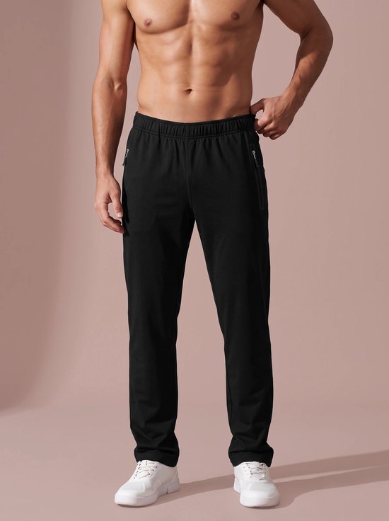 Model draagt zwarte sportbroek met twee voorzakken met rits en witte sneakers.