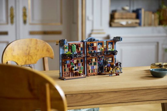 Open LEGO Boekhandel model met meubels en minifiguren, staand op een houten tafel.