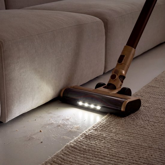 Gouden stofzuigmond met LED-verlichting onder een bank, zuigt vuil van laminaat en tapijt.