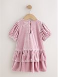 Roze fluwelen feestjurk met korte pofmouwen, pailletten en gelaagde rok, hangend aan een kledinghanger.