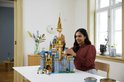 Vrouw bouwt aan het LEGO Disney Kasteel met blauwe en gouden torens, versierd met sterren.