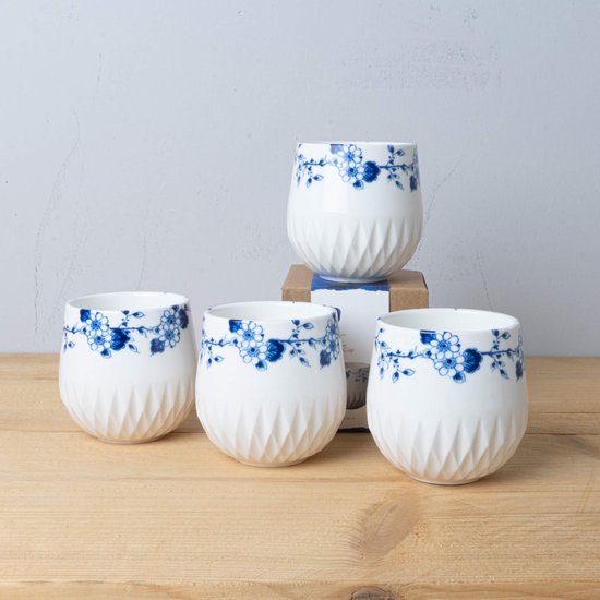 Vier witte koffiekopjes met blauwe bloemenprint en gevouwen textuur. De kopjes zijn van Heinen Delfts Blauw.